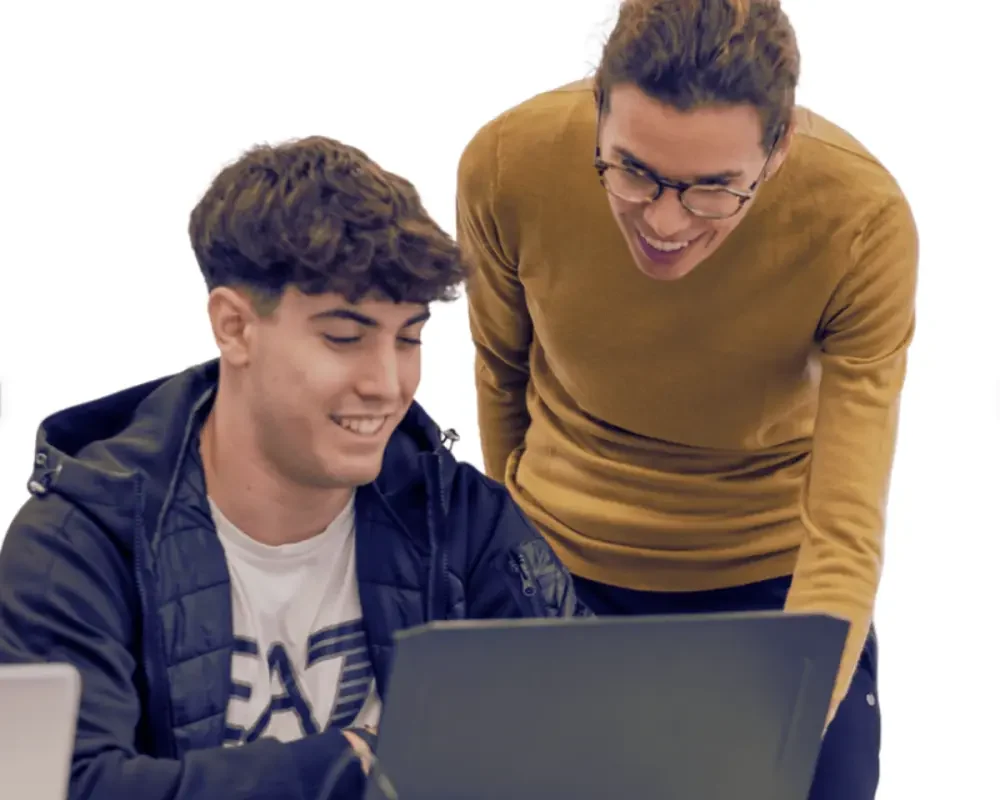 DUAL-INTENSIVO Profesora guiando a un estudiante frente a una computadora.